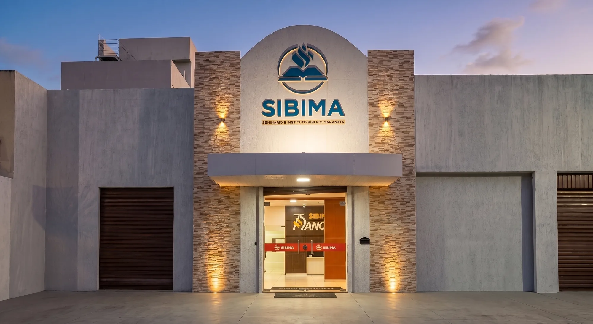 Fachada do SIBIMA ao entardecer, com o letreiro do seminário sobre a entrada
